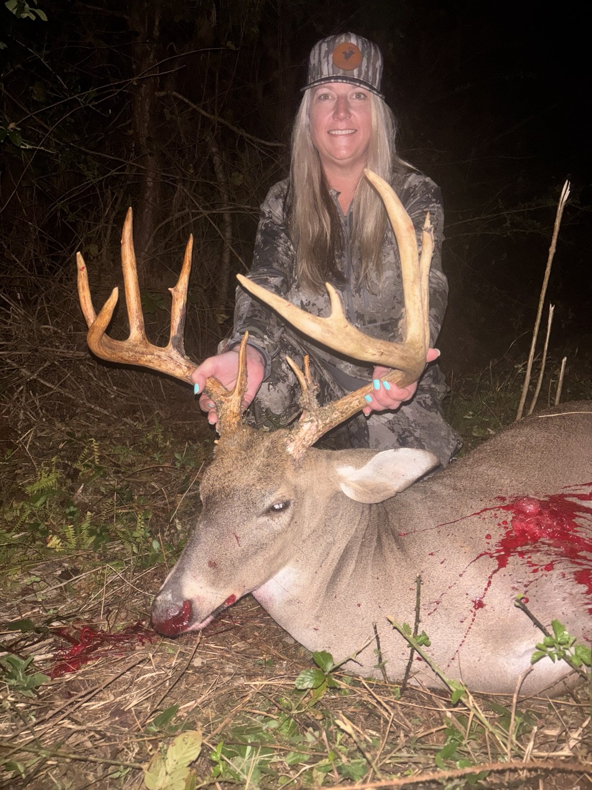 Customer posing with a harvested buck at night